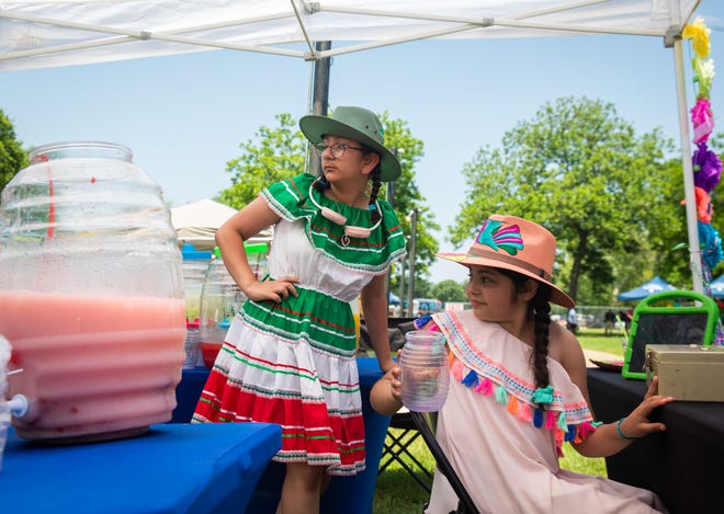 Ily Puntos, left, and Mona Soto convey Aguas Frescas orders to others from the Cheetah Booster Club running the stand at the Fiesta Austin Cinco De Mayo Celebration at Fiesta Gardens, May 7, 2022. The celebration of the holiday is dedicated to preserving hispanic culture in East Austin, and included food, dancing, music and games.